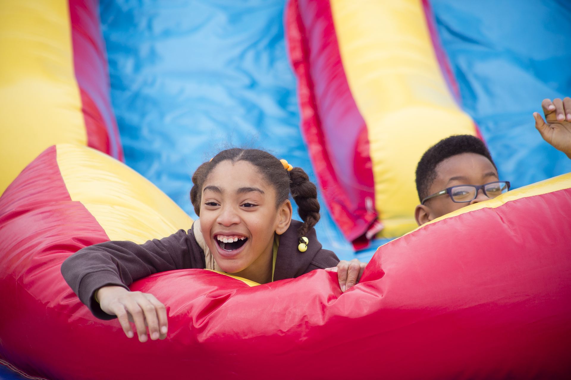 A Sunshine Band girl laughing with joy on the bounce house slide